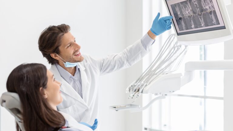 Cheerful male dentist in Round Rock showing X-ray results to his patient